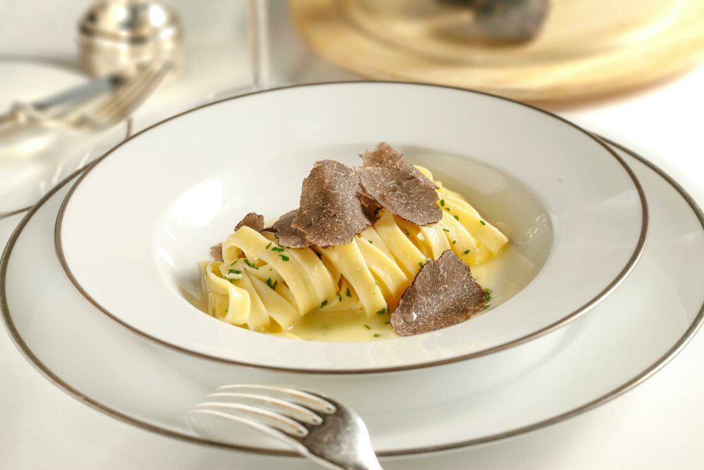 Close-up of gourmet pasta with truffle shavings served on a luxurious white plate, perfect for a fine dining experience.